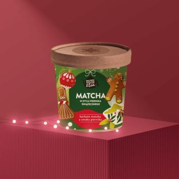 Świąteczny deser matcha Good Food w zielonym opakowaniu z piernikiem i kokardą, widok z przodu na czerwonym tle.