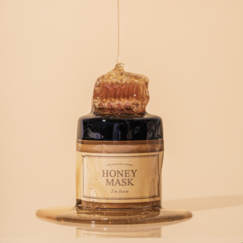 I'm From Honey Mask, nawilżająca maska miodowa. Złocisty miód z plastrem spływa ze słoika na beżowe tło.