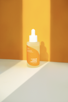 Isntree C-Niacin Toning Ampoule, rozświetlająca ampułka, żółta butelka z kroplomierzem na pomarańczowym tle.