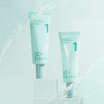 Dwie jasnoniebieskie tubki filtru SPF50+ PA++++ Clear Filter, na białych podstawkach, z rozbryzgami wody.
