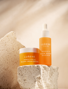 Lumene Nordic-C Valo: krem rozświetlający SPF 30 i serum, pomarańczowe opakowania na kamieniach, widok z przodu.