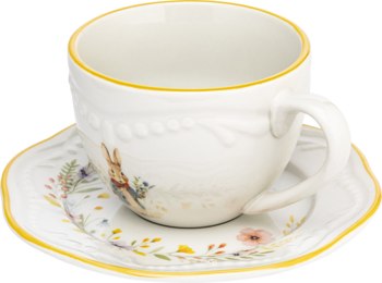 Biała ceramiczna filiżanka i spodek z żółtymi brzegami, wzorem królika, kwiatów i żłobieniami, z boku.