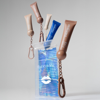 Pięć przenośnych balsamów do ust Everybody, nude i niebieski, z karabińczykami, zawieszonych nad holograficzną saszetką.