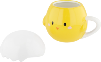 Żółty ceramiczny kubek w kształcie pisklaka z białym uchem, obok biała, pęknięta pokrywka skorupka.