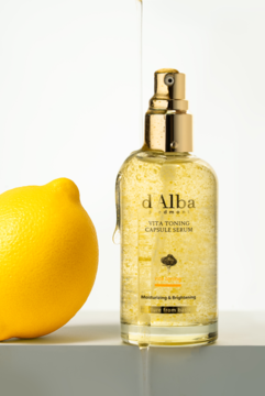 Serum tonujące d'Alba Vita Toning z witaminą C i truflem, złota butelka, obok cytryna, płyn spływa po butelce.