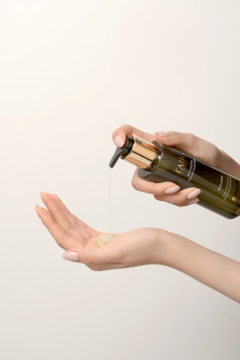 d'Alba Balancing Vegan Cleanser: Ręka dozuje wegański żel do mycia twarzy z ciemnej butelki z pompką na otwartą dłoń.