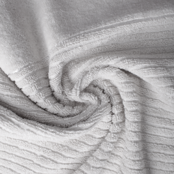 Zbliżenie na puszysty, biały ręcznik z żebrowanym wzorem, ułożony w miękkie fałdy, podkreślające teksturę.