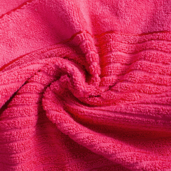 Zbliżenie na jaskraworóżowy, puszysty materiał frotte z prążkowaną strukturą, miękko ułożony w fałdy.