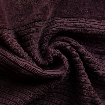 Zbliżenie na miękki, pluszowy, burgundowy materiał z prążkami, złożony w eleganckie fałdy, podkreślając teksturę.