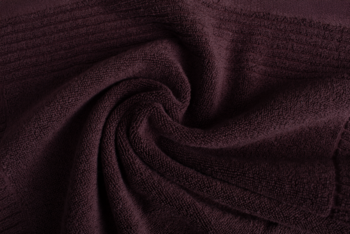 Ciemnobordowy, miękki dzianinowy materiał w puszystych, spiralnych fałdach, z delikatnymi prążkami. Widok z góry.