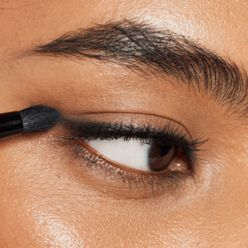 Zbliżenie oka z pędzelkiem e.l.f. rozcierającym ciemny eyeliner na dolnej powiece do smoky eye.