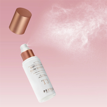 Biała butelka Pestlo T3 Glow Serum Mist z miedzianą nakrętką, unosząca się i rozpylająca mgiełkę na różowym tle.