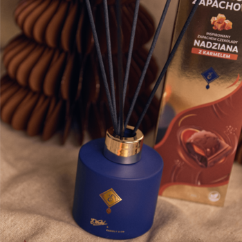 Granatowy dyfuzor zapachowy E. Wedel x Candly & Co o zapachu czekolady karmelowej, obok złote pudełko.