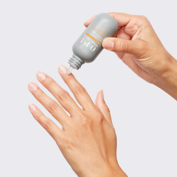 Kobieca dłoń aplikuje żel OPI Nature Strong zmiękczający skórki z szarej butelki na paznokieć.