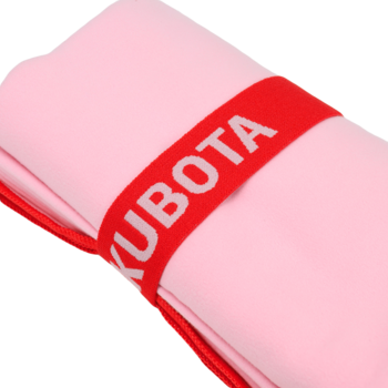 Różowy ręcznik KUBOTA zwinięty w rulon, z czerwoną opaską z białym napisem, widok z bliska pod kątem.