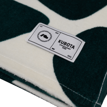 Detal ręcznika Kubota w zielono-kremowe wzory, z naszytą białą metką z logo Kubota i rokiem 2023.