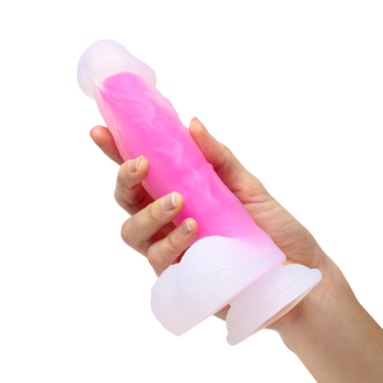 Realistyczne różowe dildo z żebrowanym trzonem i białą przyssawką, trzymane w dłoni, widok z boku.