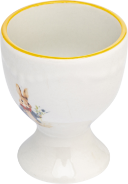 Kremowy kieliszek na jajko z żółtym rantem i uroczym królikiem Piotrusiem na boku, widok pod kątem.