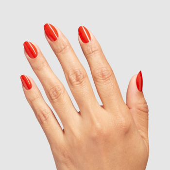 Widok z góry na kobiecą dłoń z długimi, owalnymi paznokciami pomalowanymi na jaskrawo czerwony, błyszczący lakier.