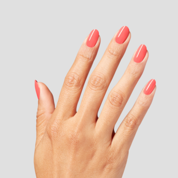 Ręka z błyszczącym koralowym lakierem do paznokci, widok od tyłu. Pięć paznokci pomalowanych, na jasnoszarym tle.