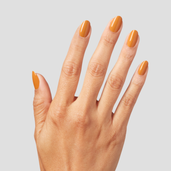 Dłoń z paznokciami pomalowanymi na intensywny, błyszczący lakier w kolorze musztardowym. Widok od góry.
