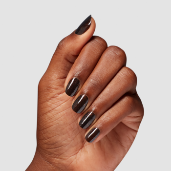 Błyszczący, ciemnobrązowy lakier do paznokci na ciemnej dłoni. Krótkie, owalne paznokcie, ujęcie z góry.