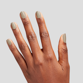 Ciemniejsza dłoń z paznokciami pokrytymi klasycznym, oliwkowym lakierem. Widok od wewnętrznej strony na jasnym tle.