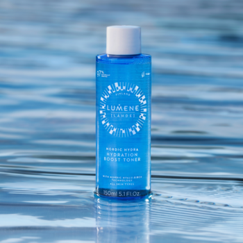 Lumene Nordic Hydra Toner, nawilżający tonik w niebieskiej butelce z białą nakrętką, widok z przodu na tle wodnej tafli.