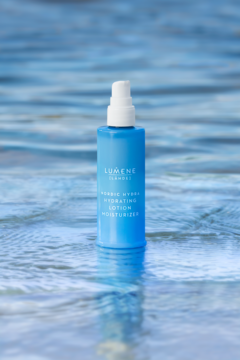 Lumene Nordic Hydra lotion nawilżający do twarzy w niebieskiej butelce z atomizerem, na tle błękitnej wody.