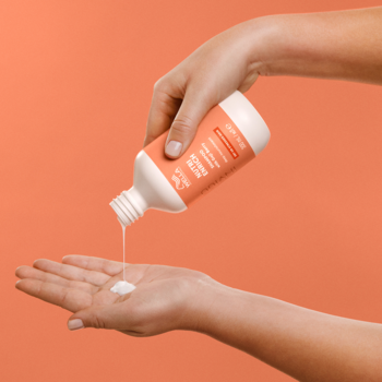 Wella Invigo Nutri-Enrich szampon do suchych włosów, wylewany z pomarańczowej butelki na otwartą dłoń.