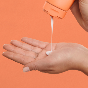 Głęboko pielęgnująca odżywka Invigo Nutri-Enrich, biały krem wylewający się z pomarańczowej butelki na dłoń.