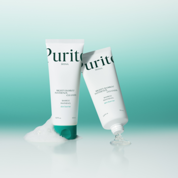 Dwie białe tubki Purito Mighty Bamboo Panthenol Cleanser, żelu do twarzy, na turkusowym tle. Widoczna piana i żel.