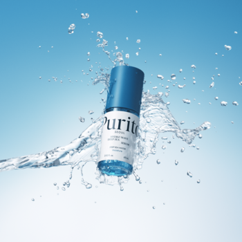 Purito serum nawilżające w błękitnej butelce, unoszące się w powietrzu, otoczone chlapnięciem wody na jasnoniebieskim tle.