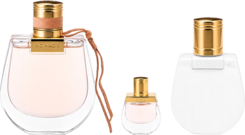 Chloé Nomade zestaw: dwie beżowe wody perfumowane i biały balsam do ciała na czarnym tle, złote korki.