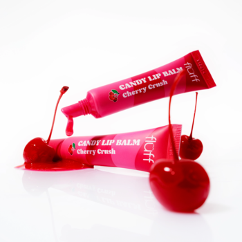 Dwa różowe balsamy Fluff Candy Lip Balm Cherry Crush w tubkach, z wylanym balsamem i świeżymi wiśniami.