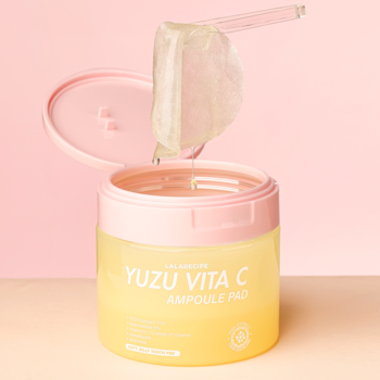 Otwarty, żółty słoiczek YUZU VITA C Ampoule Pad z różową nakrętką. Jeden przezroczysty, żelowy płatek uniesiony.