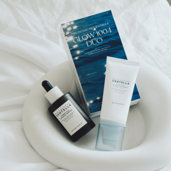 Zestaw Skin1004 Centella Glow Duo: ampułka Probio-Cica, krem Hyalu-Cica SPF50+ i niebieskie pudełko na białej tkaninie.