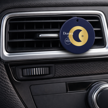 Okrągły, granatowy odświeżacz Donez z złotym księżycem, wpięty w czarną kratkę wentylacyjną samochodu.