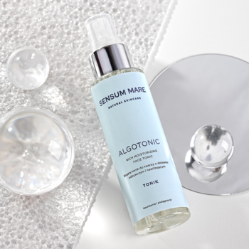Sensum Mare Algotonic tonik nawilżający w miętowej butelce z atomizerem na białym, teksturowanym tle z kulami i lustrem.