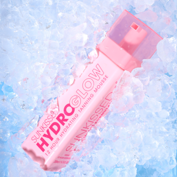 Sunkissed Hydro Glow 12 Hour Hydrating Tanning Mousse w różowej butelce na tle kruszonego lodu, widok z góry.