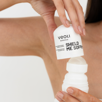 Dłonie otwierają biały mineralny dezodorant Veoli Botanica Shield Me Soft, widoczny aplikator roll-on.