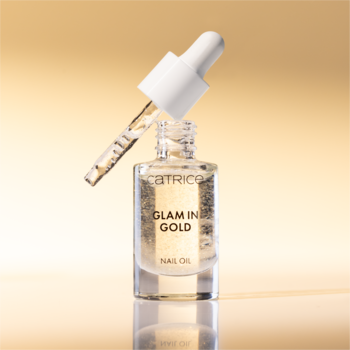 Zbliżenie na Catrice Glam In Gold Nail Oil, przezroczysty olejek z drobinkami złota w butelce z uniesioną pipetą.