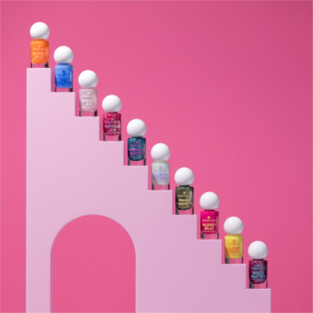 Jedenaście mini lakierów do paznokci essence w różnych kolorach, z białymi nakrętkami, ułożonych na różowych schodach.