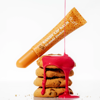 Pomarańczowy Fluff Candy Lip Balm Crumbl Cookie nad ciastkami z różową polewą, ujęcie studyjne.