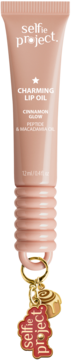 Selfie Project Charming Lip Oil Cinnamon Glow in a peach tube with a gold charm and red logo, front view.