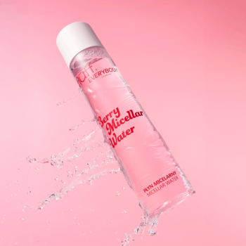 Płyn micelarny Fluff Berry w butelce z różowym płynem, pod kątem, z rozbryzgami wody na różowym tle.