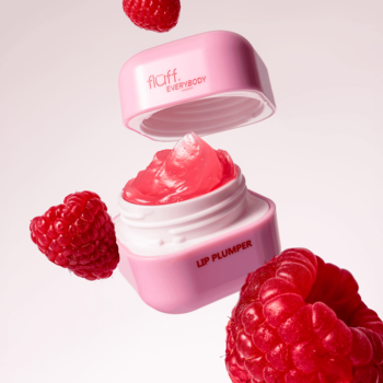 Różowy lip plumper Fluff Kiss Me Berry otwarty, z obfitym malinowym żelem i latającymi dookoła świeżymi malinami.