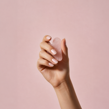 Dłoń trzyma sercowaty różowy kwarc na pastelowym tle. Lakier-kuracja do paznokci GLOV Rose Quartz Active.