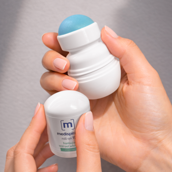 Medispirant roll-on 72h, biały antyperspirant redukujący pot, trzymany w dłoniach, widoczna niebieska kulka.