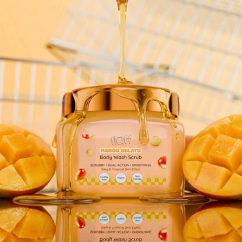 Słoik peelingu Fluff Mango Gelato z lejącym się miodem, obok świeże połówki mango, widok z przodu.